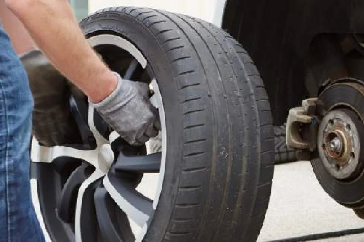 Person wechselt mit einem Schlagschrauber einen Autoreifen.